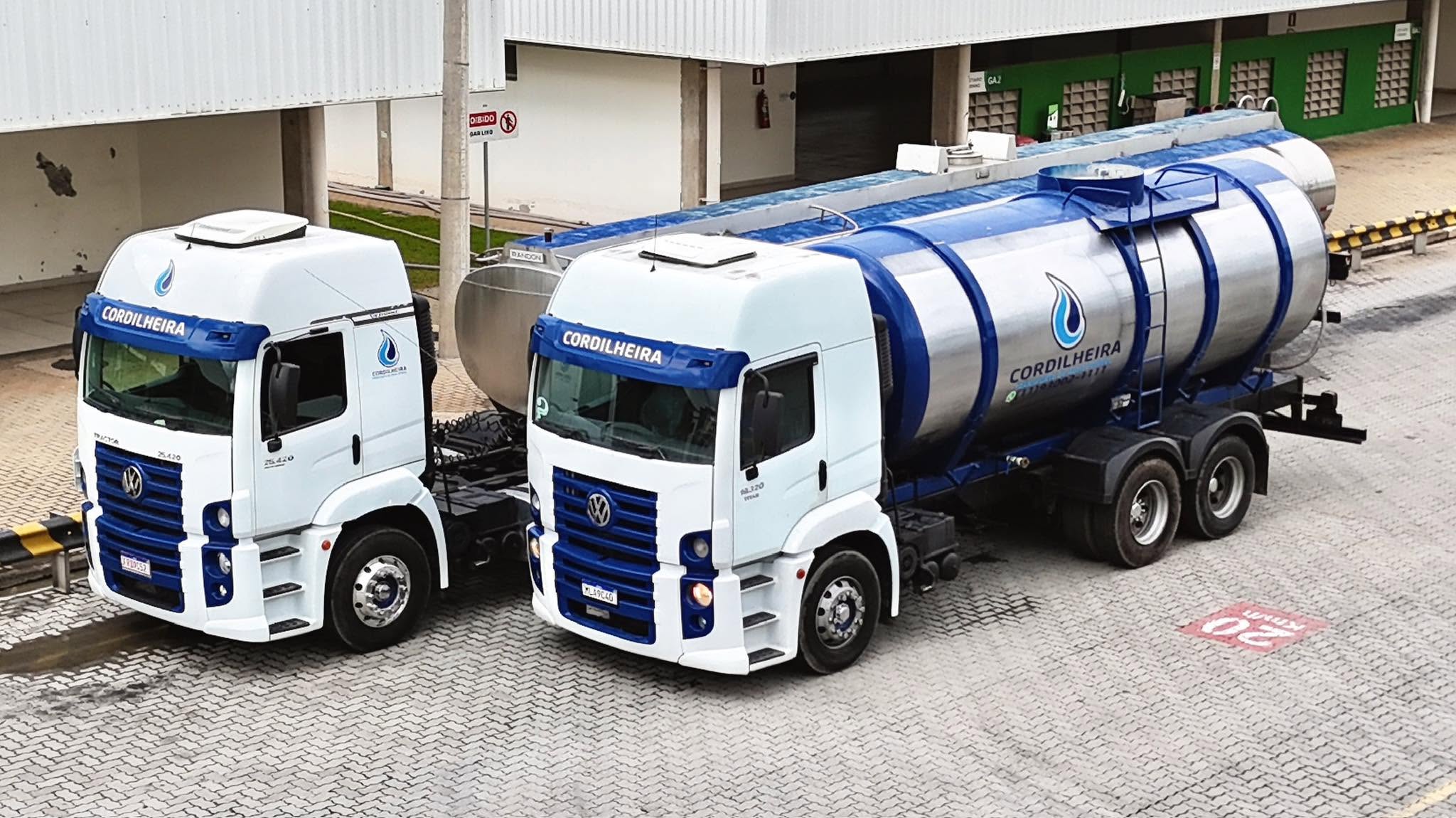 Dois caminhões Cordilheira, um deles com tanque inox acoplado, em pátio de carregamento